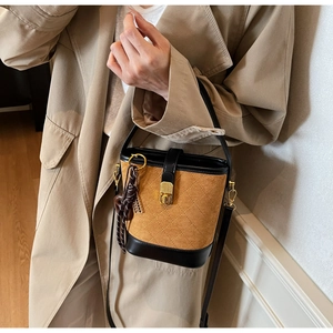 Detail of vintage quilted leather bucket bag with gold hardware and tassel charm on model