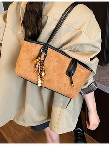 Retro tan quilted tote bag with wooden bead charm and black handles shown on a model