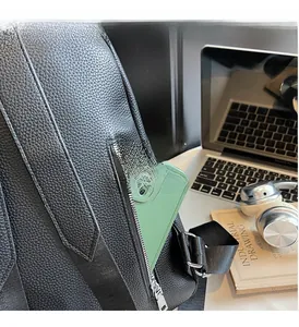 Close-up of black pebble leather backpack side pocket with a phone and silver zipper