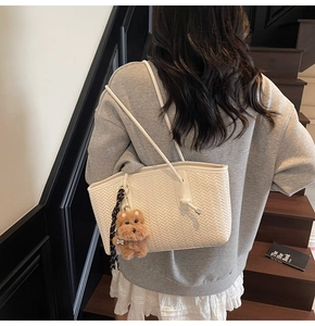 Détail du sac cabas blanc tissé avec motif en V et pendentif charmant en forme de chien