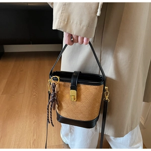 Detail view of vintage quilted bucket bag featuring brown suede and golden twist lock