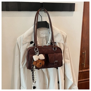 Close-up of chocolate brown Boston bag with multi-pocket design and a cute bear charm