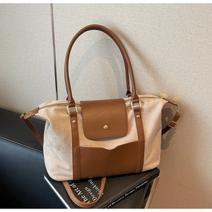 Détail du sac cabas en daim beige avec accents en cuir marron et finitions dorées