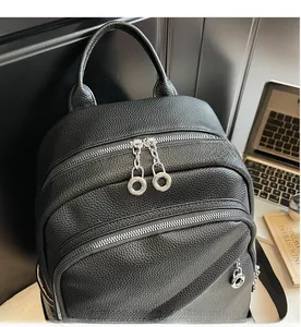 Detail of smooth silver metal zippers and lychee grain leather on a black backpack