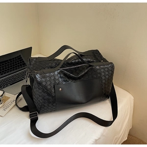 Dettaglio borsa da viaggio in pelle intrecciata nera con tracolla e libro Matisse