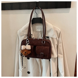 Detail of dark brown matte Boston bag with plush bear charm and buckle pocket detailing