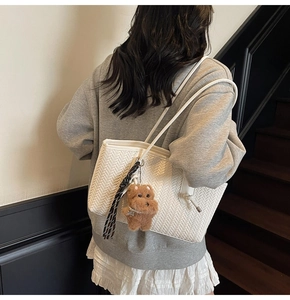 Détail du sac cabas blanc tissé avec texture en V et charmant pendentif chiot marron