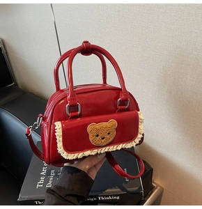 Detail of red glossy mini bag featuring white lace trim and a cute plush bear applique