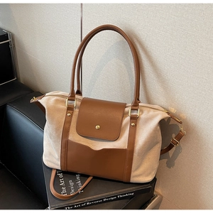 Détail du sac cabas en daim beige avec anses en cuir marron et finitions dorées