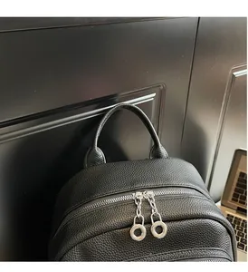 Close-up of black leather backpack with lychee grain texture and metal ring zippers