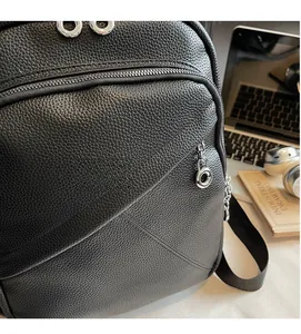 Close-up of black lychee grain texture backpack with silver hardware and ring zippers