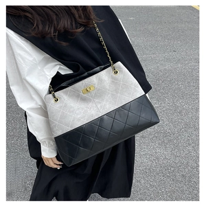 Detail of quilted suede tote with grey-black patchwork, gold twist lock, and chain strap