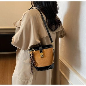 Detail of vintage quilted bucket bag in brown suede with black leather strap and gold lock