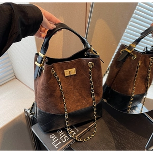 Detail of suede bucket bag featuring diamond-quilted leather and a gold chain strap