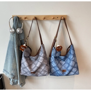Detailed view of quilted tote bags in grey and denim blue with plush monster charms