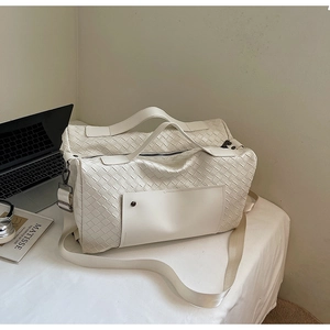 Dettaglio borsa da viaggio bianca intrecciata con tracolla regolabile e ampio spazio