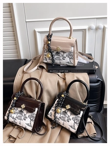 Three stylish landscape print crossbody bags with round handles on a leather sofa
