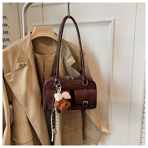 Detail of burgundy suede Boston bag with double zippers and cute bear plush charm accessory