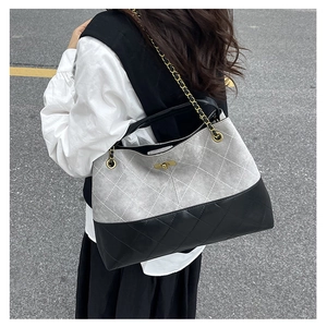 Detail of vintage suede tote bag with grey and black diamond quilting and gold chain strap