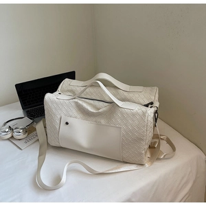 Dettaglio borsa da viaggio in pelle bianca intrecciata con laptop e accessori