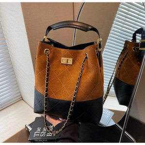 Detail of vintage suede bucket bag featuring quilted leather panels and gold chain strap