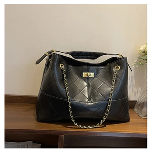 Detailed view of black quilted tote bag with golden turn-lock and chain handle