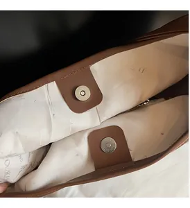 Detail of bag interior with brown leather trim, branded jacquard lining and magnetic snaps
