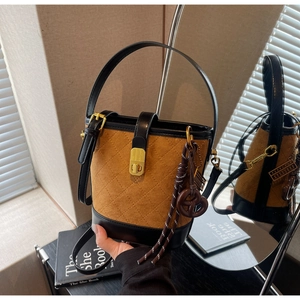 Detail of vintage brown suede bucket bag with quilted stitching and gold twist lock