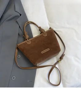 Detail of brown suede tote bag featuring leather knots and adjustable shoulder strap