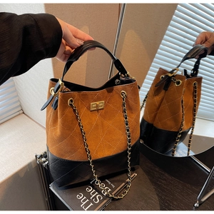 Detail of vintage brown suede and black leather patchwork bucket bag with golden lock