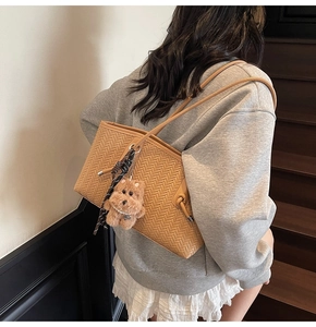 Détail du sac fourre-tout tissé camel avec texture chevron et breloque ours en peluche