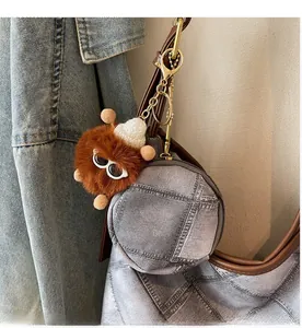 Detail of denim coin purse and plush monster charm with golden clasp on handbag