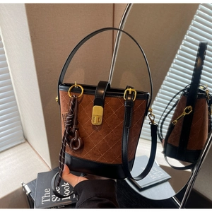 Detail of vintage brown suede bucket bag with quilted patterns and golden turn-lock