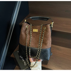Detail of vintage faux suede bucket bag with contrast leather and gold chain strap