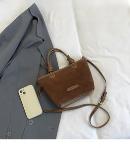 Detailed comparison of the dark brown suede bucket bag size next to a smartphone