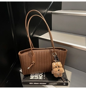 Détail du sac cabas marron vintage tressé avec de longues anses et un charme de chiot