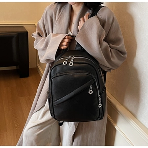 Close-up of black pebble grain leather backpack with silver zippers on a female model