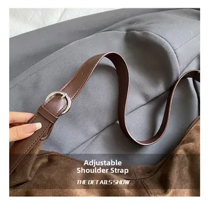 Detail of adjustable strap with silver metal buckle on brown matte shoulder bag