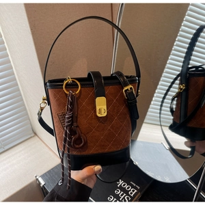 Detail of vintage brown suede bucket bag with quilted stitching and gold twist lock