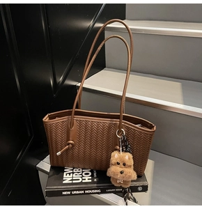Texture détaillée du cabas tressé marron avec charme de chiot en peluche sur des livres