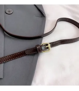 Detail view of dark brown polished leather adjustable strap with golden square buckle