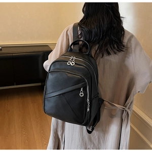 Detail of minimalist black lychee grain leather backpack on model in a home setting