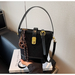 Detail of black quilted bucket bag featuring matte suede textures and gold twist lock