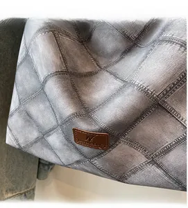 Close-up of denim printed fabric texture and brown leather brand label on bucket bag
