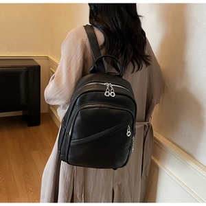Rear view of a model wearing a black lychee leather backpack with silver zippers
