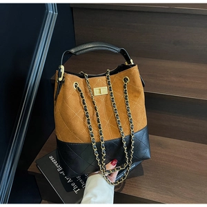 Detail of retro suede bucket bag showing contrast stitching and gold twist lock closure