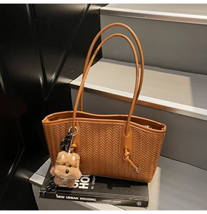 Gros plan d'un sac cabas marron tissé avec pendentif chien en peluche sur escalier