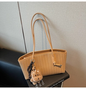 Détail d'un sac cabas tissé marron clair avec fine bandoulière et breloque chien en peluche