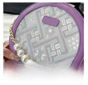 Detail of purple embroidery mini bag with large pearl strap and geometric flower pattern