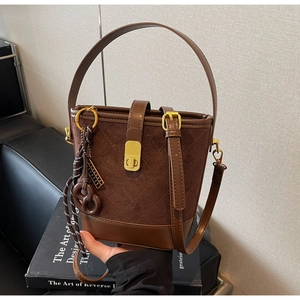 Detail of vintage brown quilted suede bucket bag with gold lock and leather handle